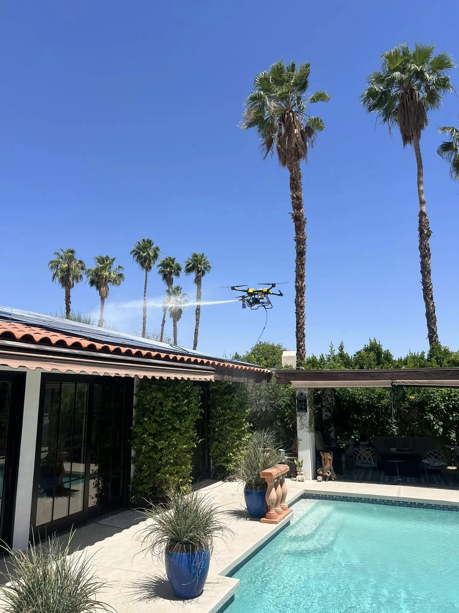 DronePower1 cleaning drone actively rinsing a rooftop solar array during a job