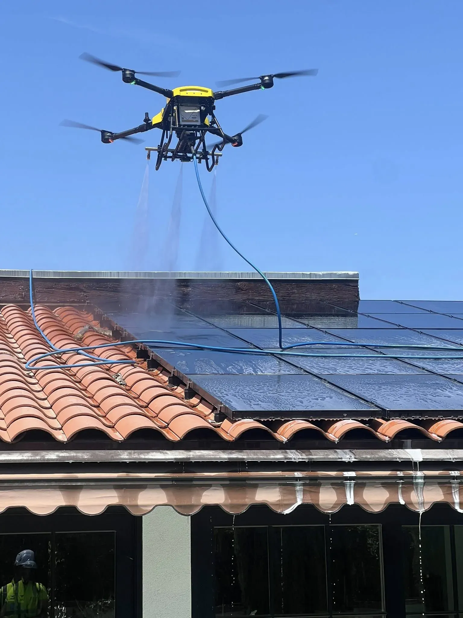 DronePower1 drone mid cleaning pass over a residential rooftop solar array
