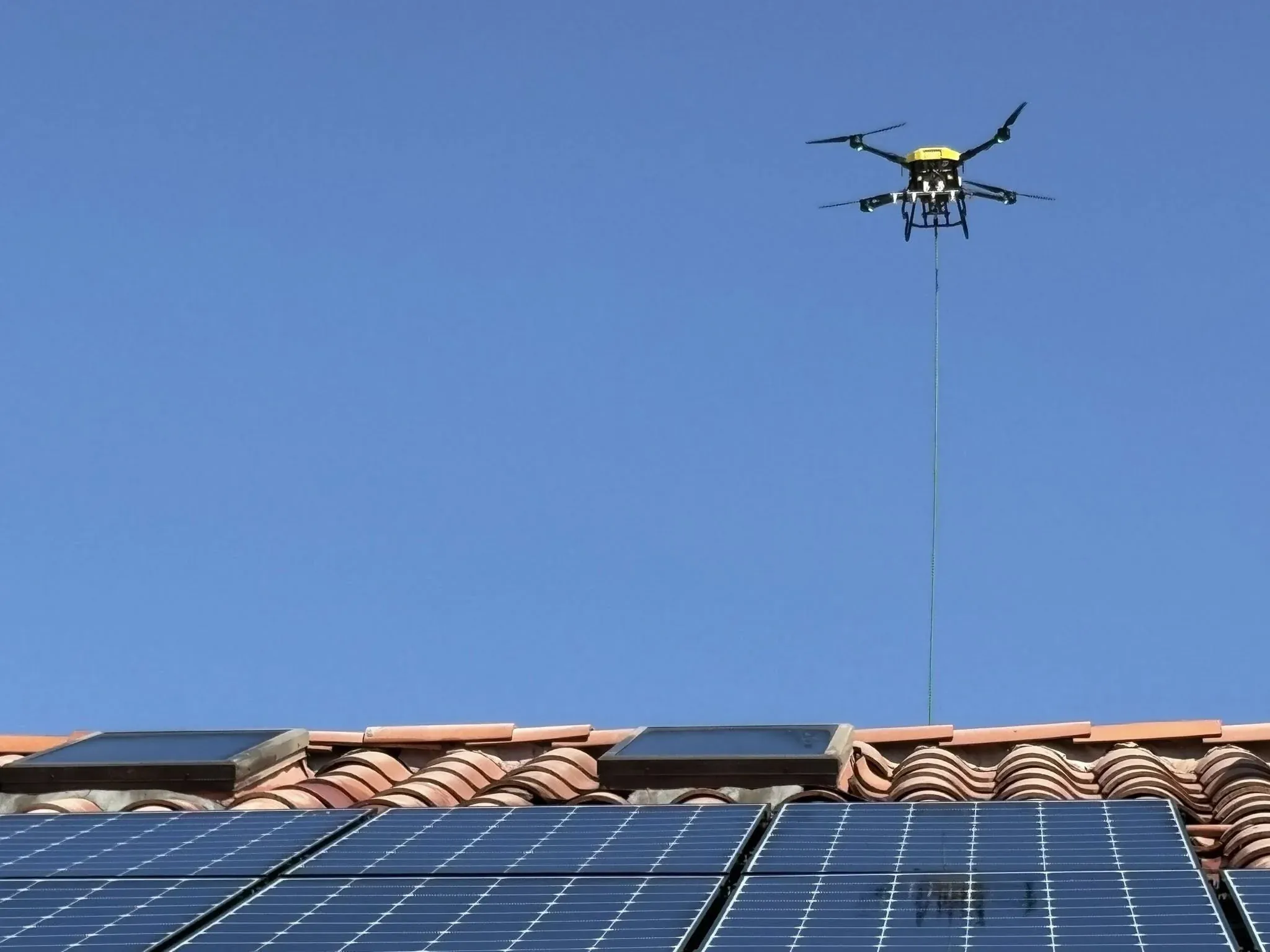Elevated action frame of a DronePower1 drone centered over a solar array during a wash