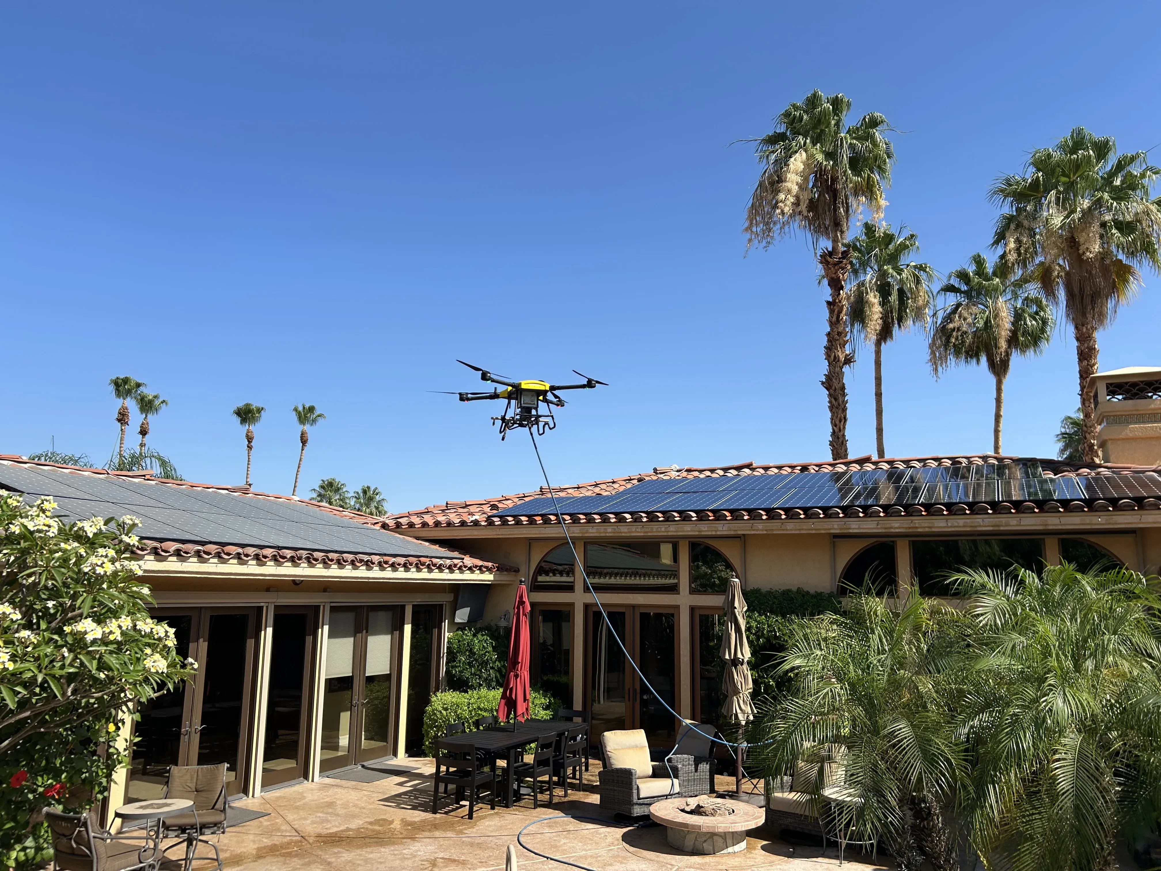 DronePower1 drone working above a palm-lined backyard roof