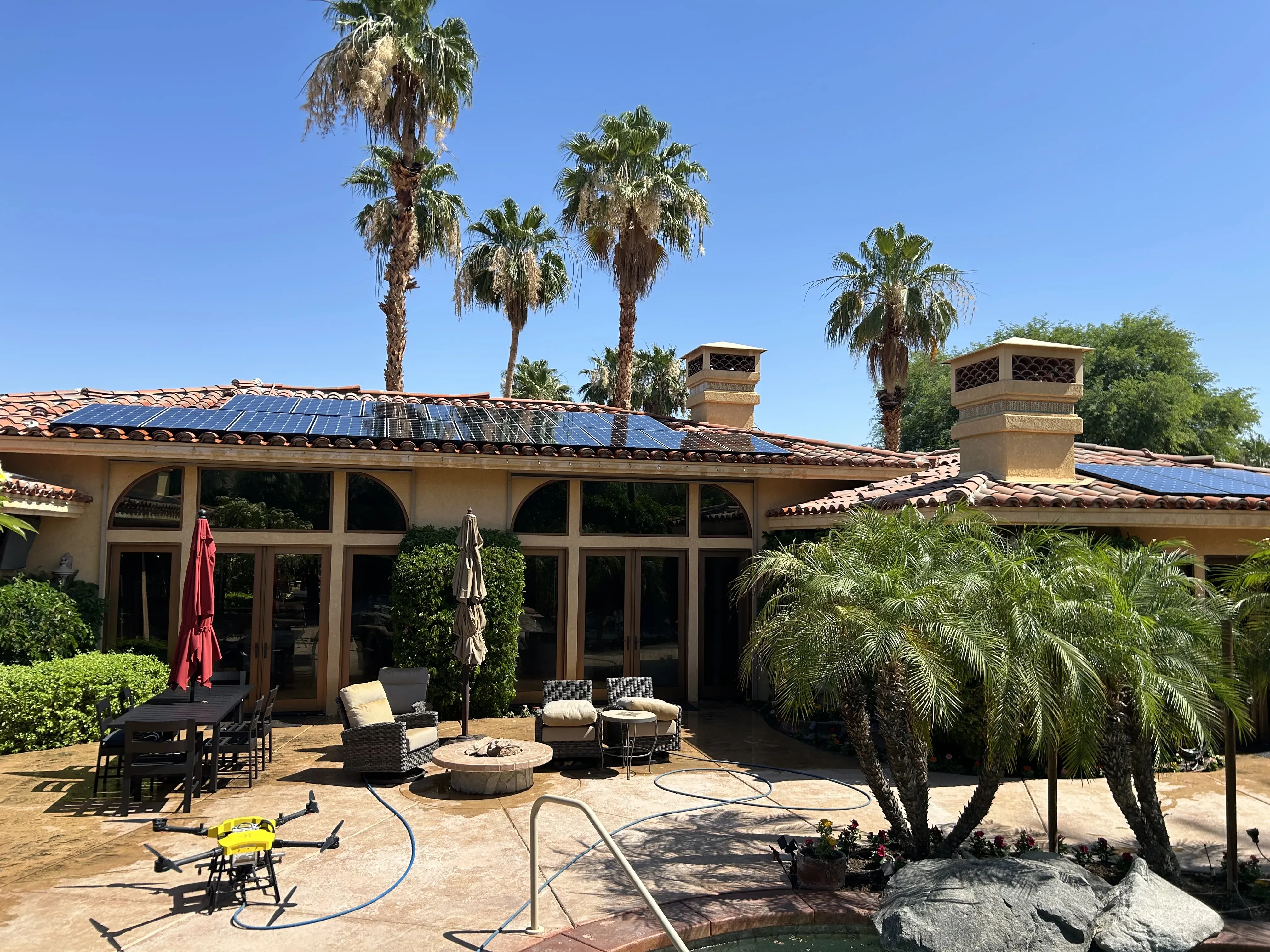 DronePower1 drone parked in a backyard with solar panels on the roof and palms overhead