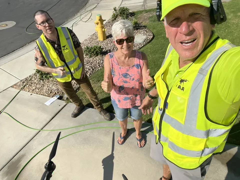 Homeowners posing with the DronePower1 operator after the drone cleaning setup