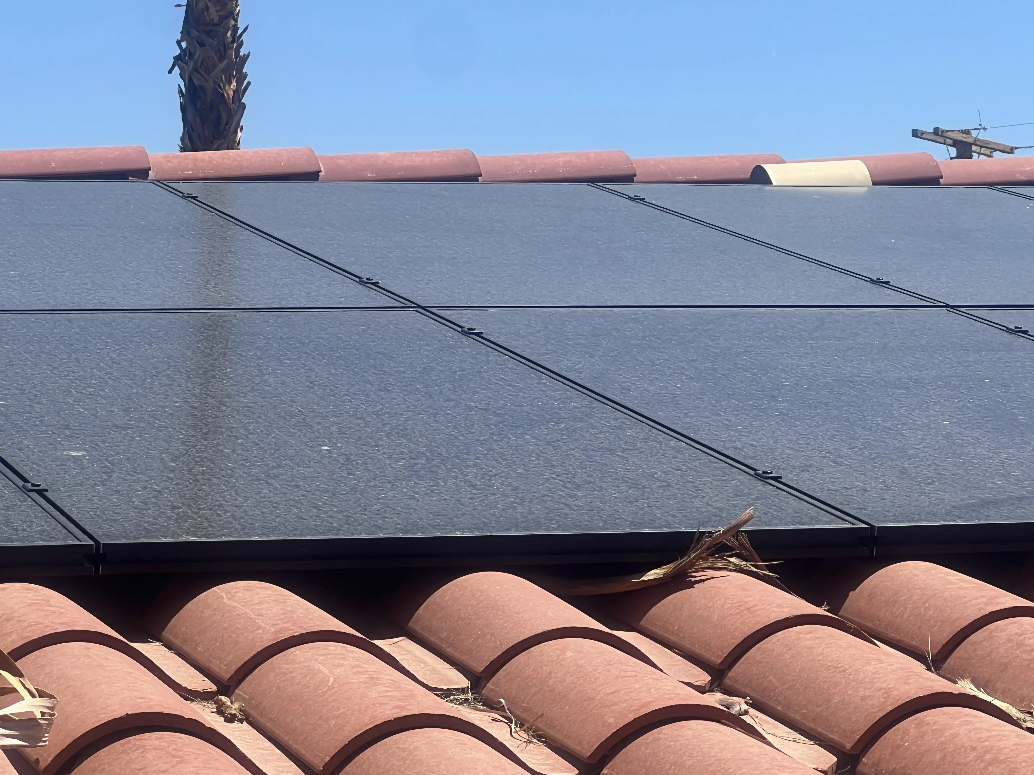 Edge of a solar panel array running along the roofline with tile texture visible