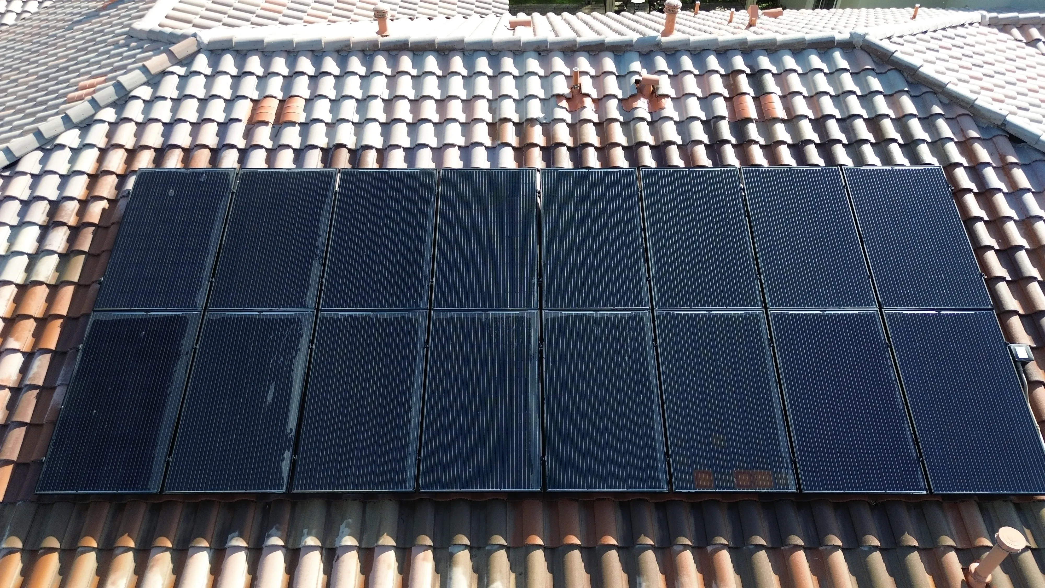 Tight overhead detail with dark solar panels filling most of the frame on a tiled roof