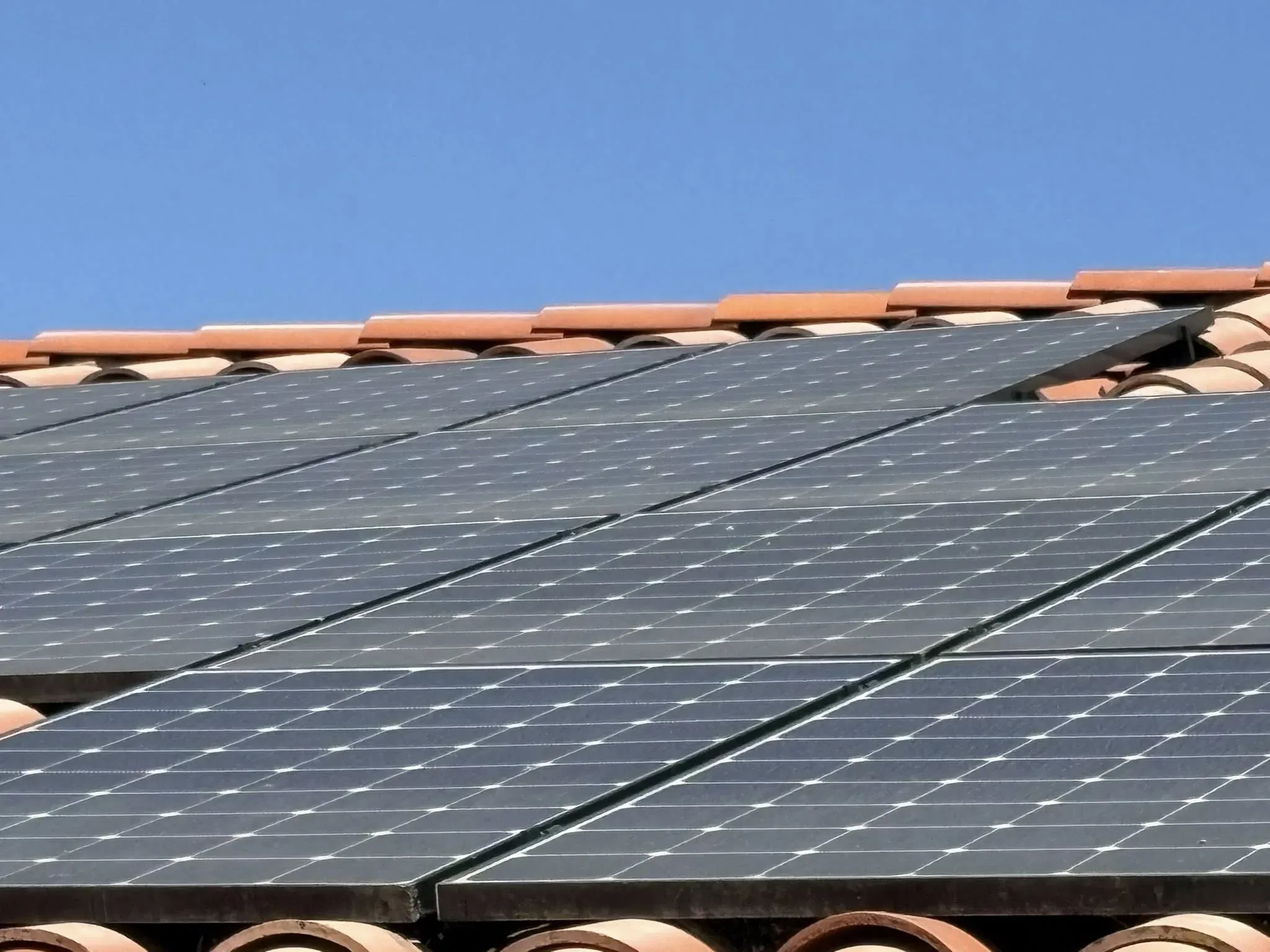 Close-up of rooftop solar panels set against a clear blue sky