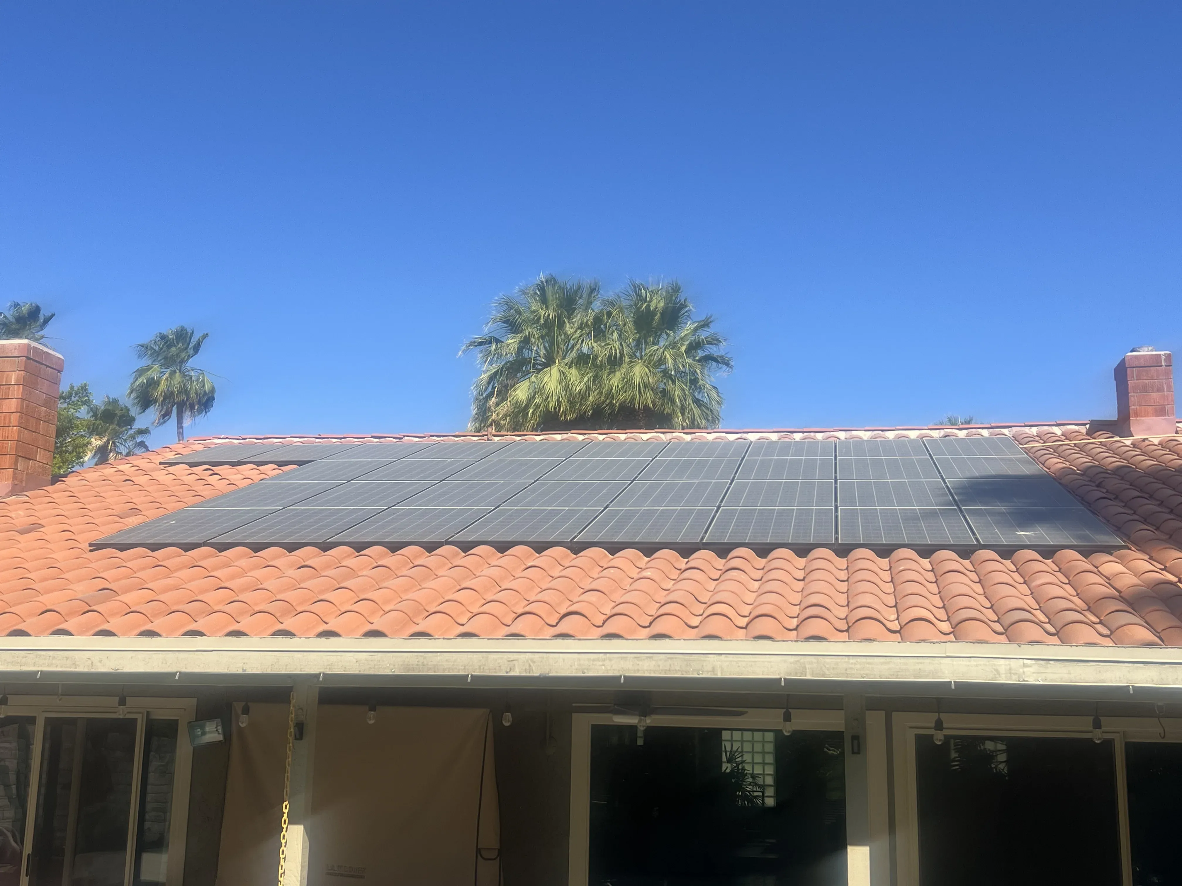 Wide tile roof with a solar array under a clear blue sky