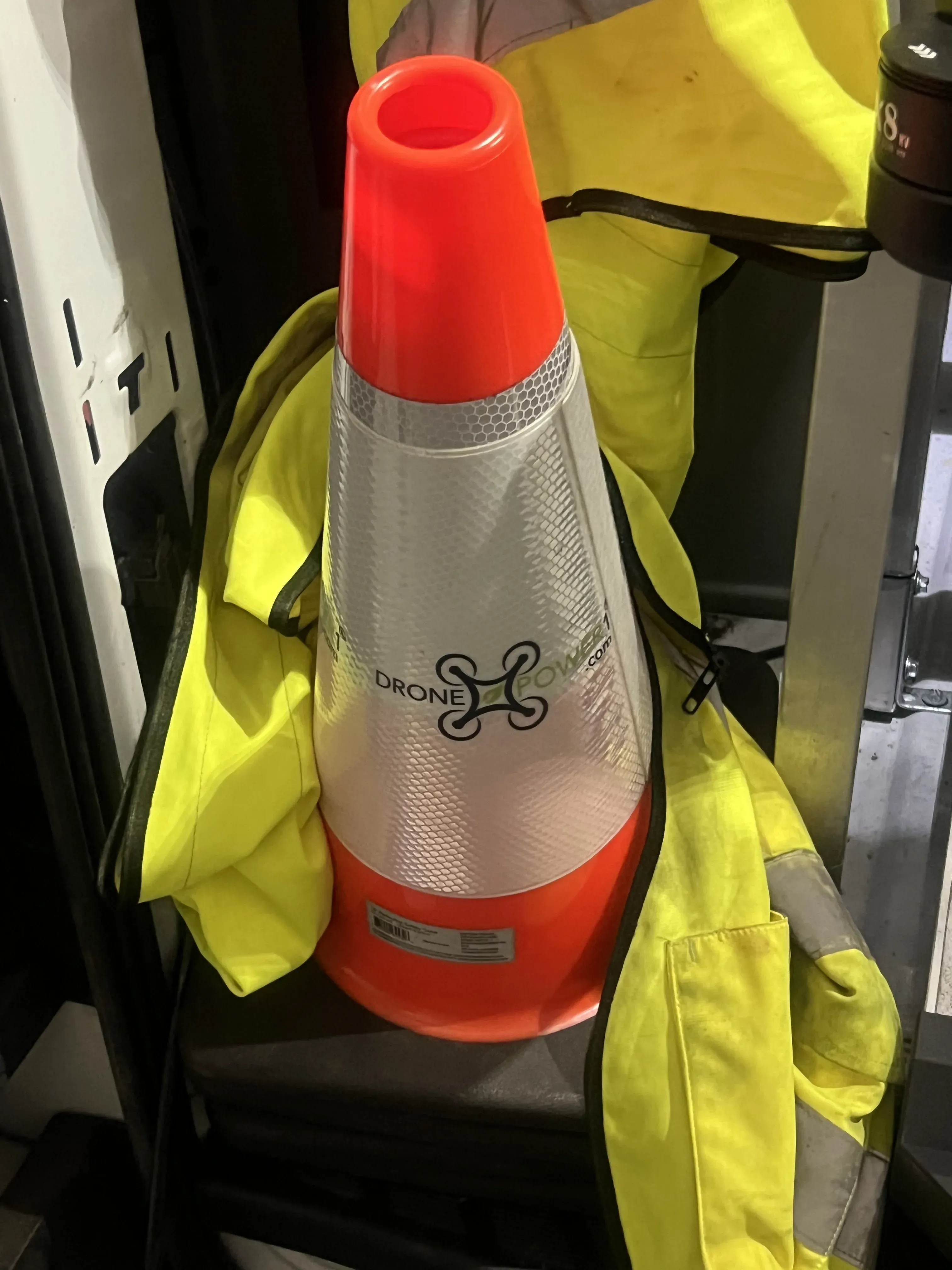 DronePower1-branded safety cone staged with the crew's high-visibility vest before a job