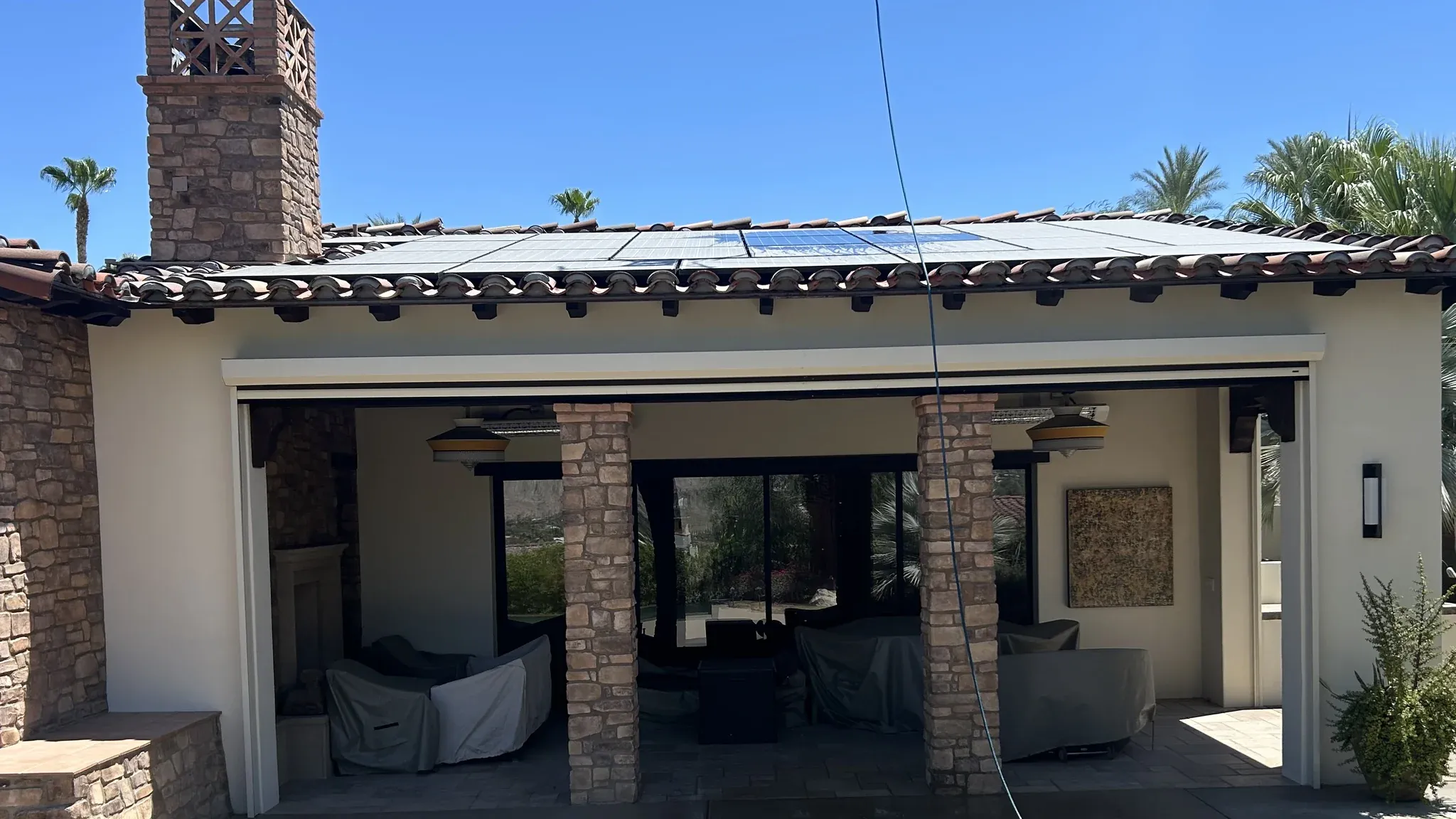 Rooftop solar array on a Spanish tile-roof home in the Coachella Valley coated in desert dust before a DronePower1 drone cleaning, the panels dulled to a pale grey haze