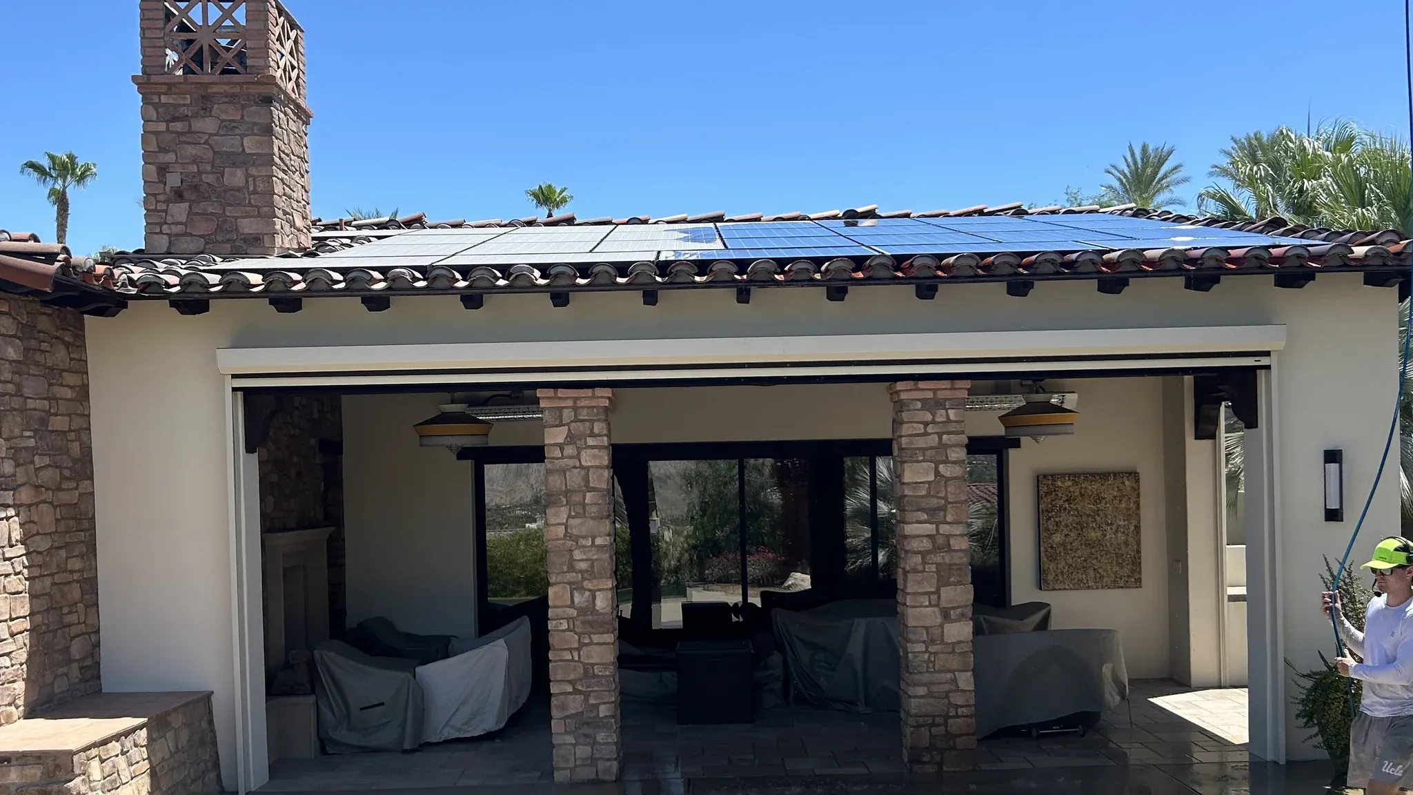 The same Coachella Valley tile-roof solar array part-way through a DronePower1 drone cleaning, the washed panels already deep blue beside the sections still coated in dust