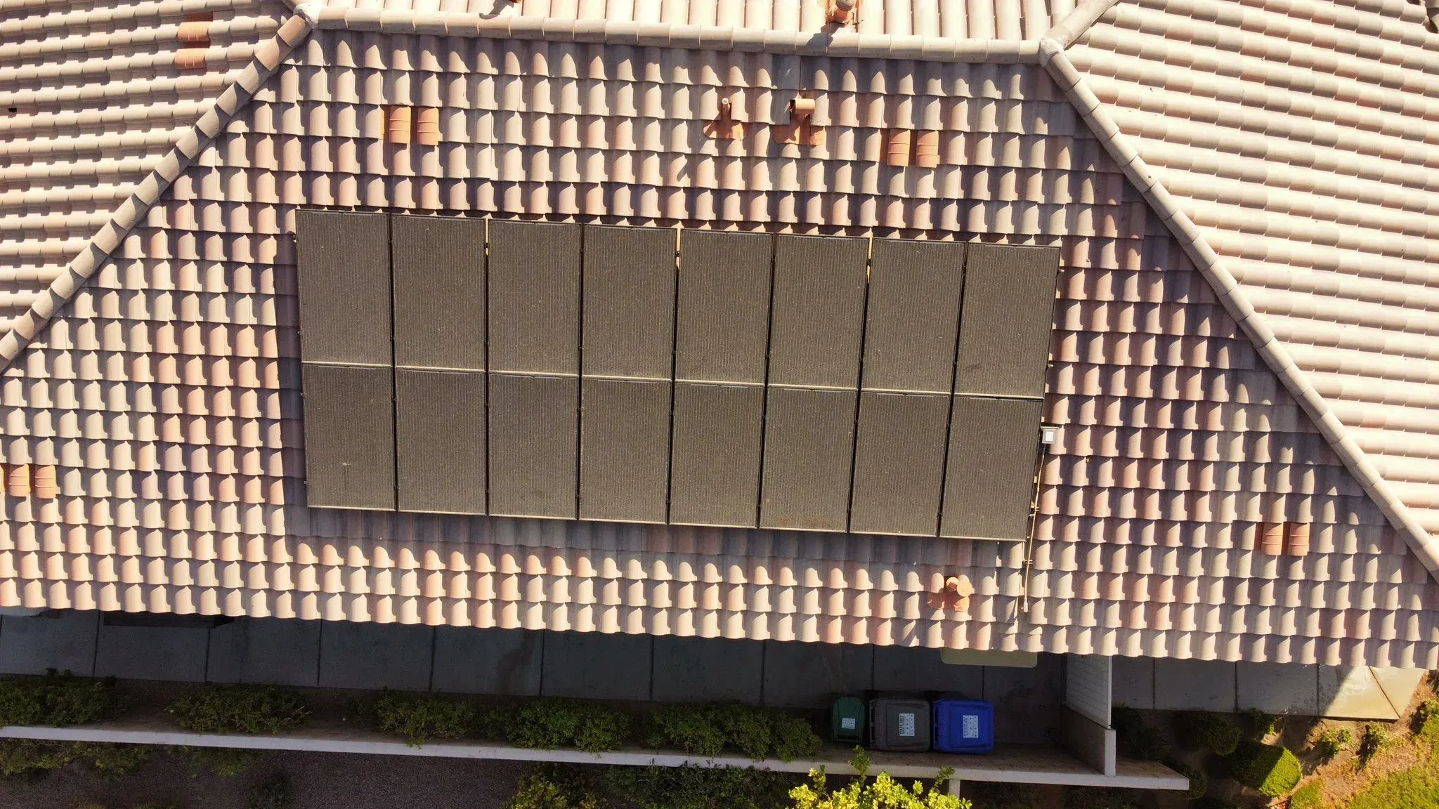 Top-down drone view of a tile-roof home with the solar panels coated in dust and grime before a DronePower1 cleaning pass