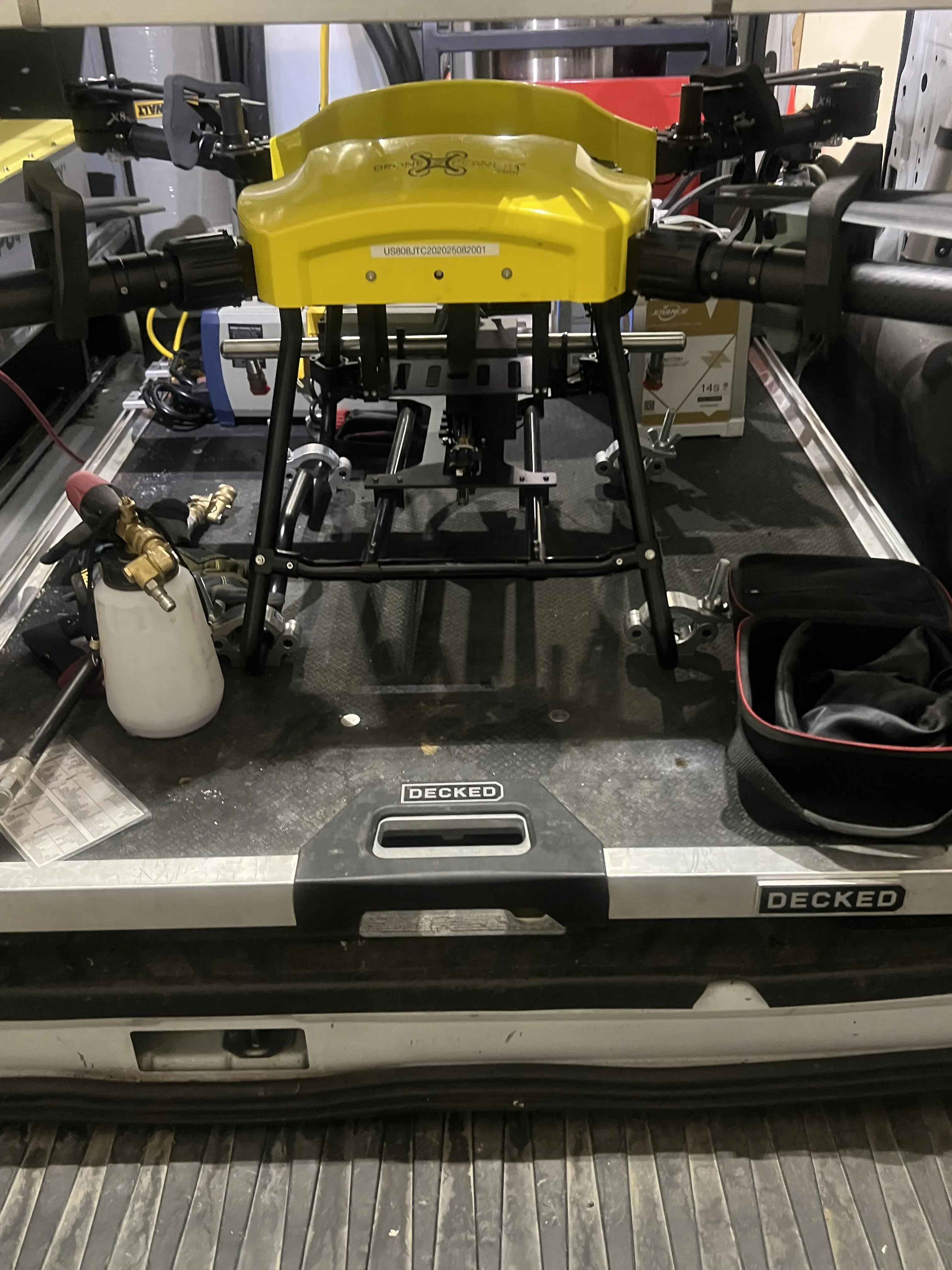 Work truck bed loaded with the DronePower1 cleaning drone, tanks, and field equipment