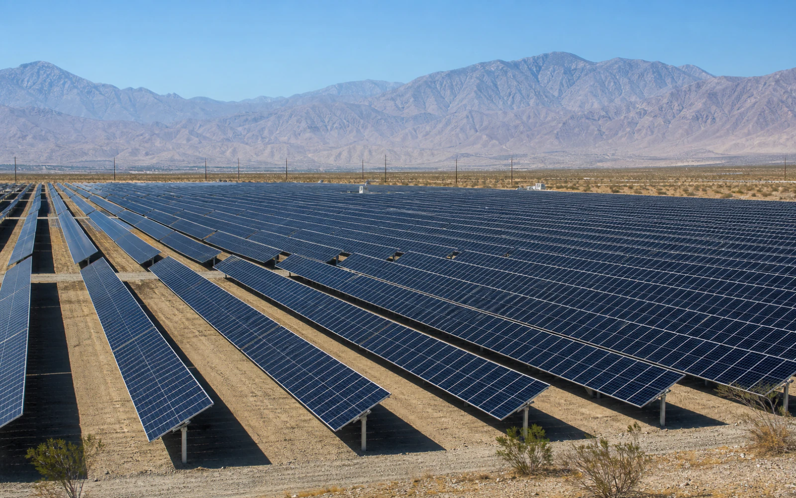 Rows of ground-mounted utility solar panels across the Coachella Valley desert
